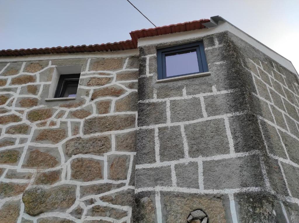 a stone building with two windows on it at Casa Penedo do Raposo in Muxagata