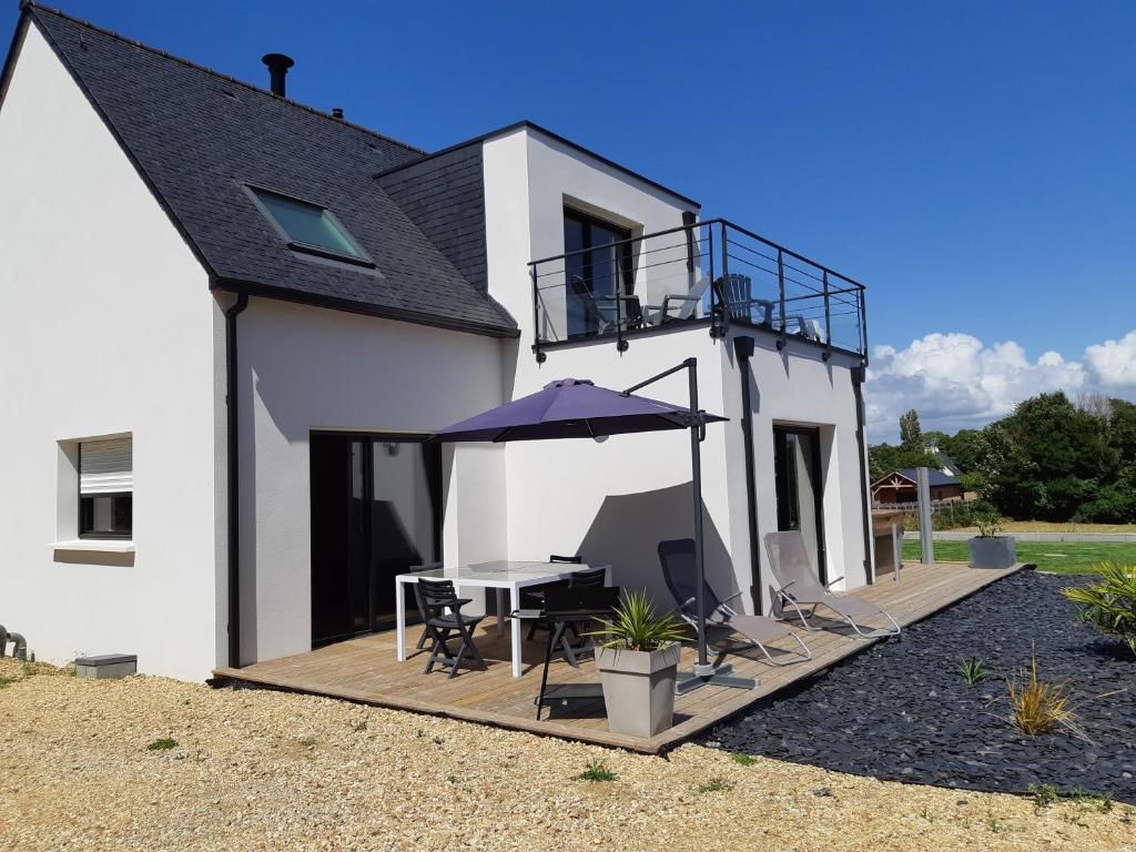 een huis met een terras met een tafel en een paraplu bij Maison à 200m des plages avec jacuzzi in Trégunc