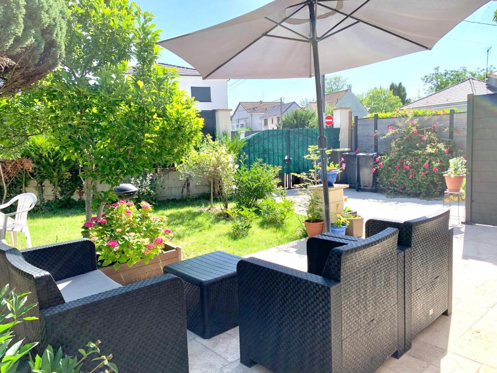 a patio with chairs and an umbrella and plants at MaisonTevy - Appart 2 Chambres-4lits-Terrasse-Jardin & Studio-Confort-Climatisation- Idéale-Pro-Tourisme in Pontault-Combault