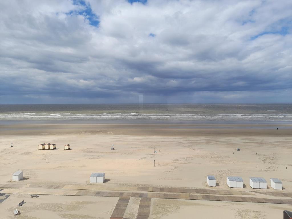 a beach with chairs and the ocean on a cloudy day at Kristof701 in De Panne