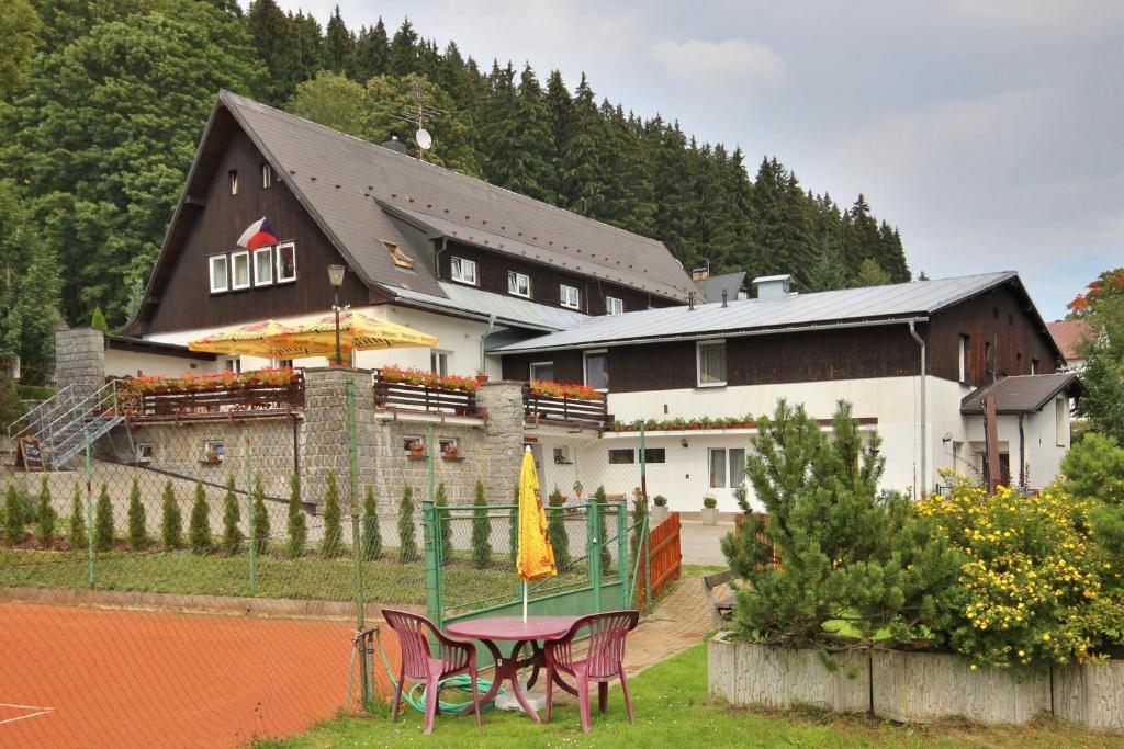 um edifício com uma mesa e cadeiras em frente em Penzion Bobešova bouda em Železná Ruda