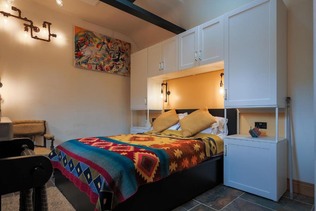 ein Schlafzimmer mit einem Bett mit einer bunten Decke in der Unterkunft Eakley Stables 2 - Pogo in Newport Pagnell