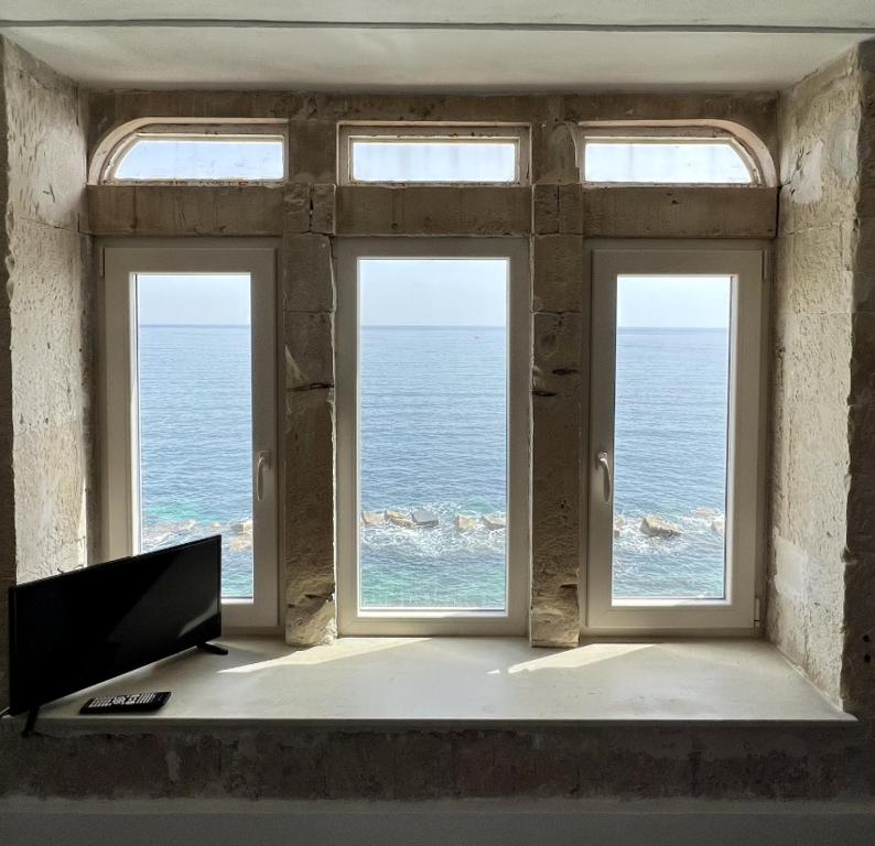 a room with two windows and a computer and the ocean at Great Charme in Siracusa