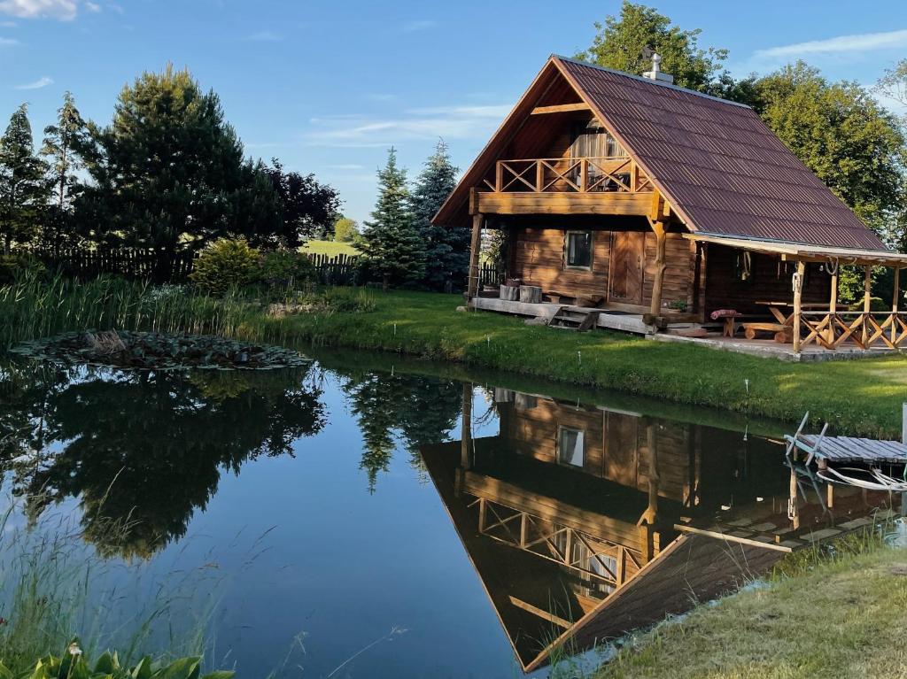 een blokhut op een meer met zijn reflectie in het water bij Namelis Atokvėpis in Čiuiniukai