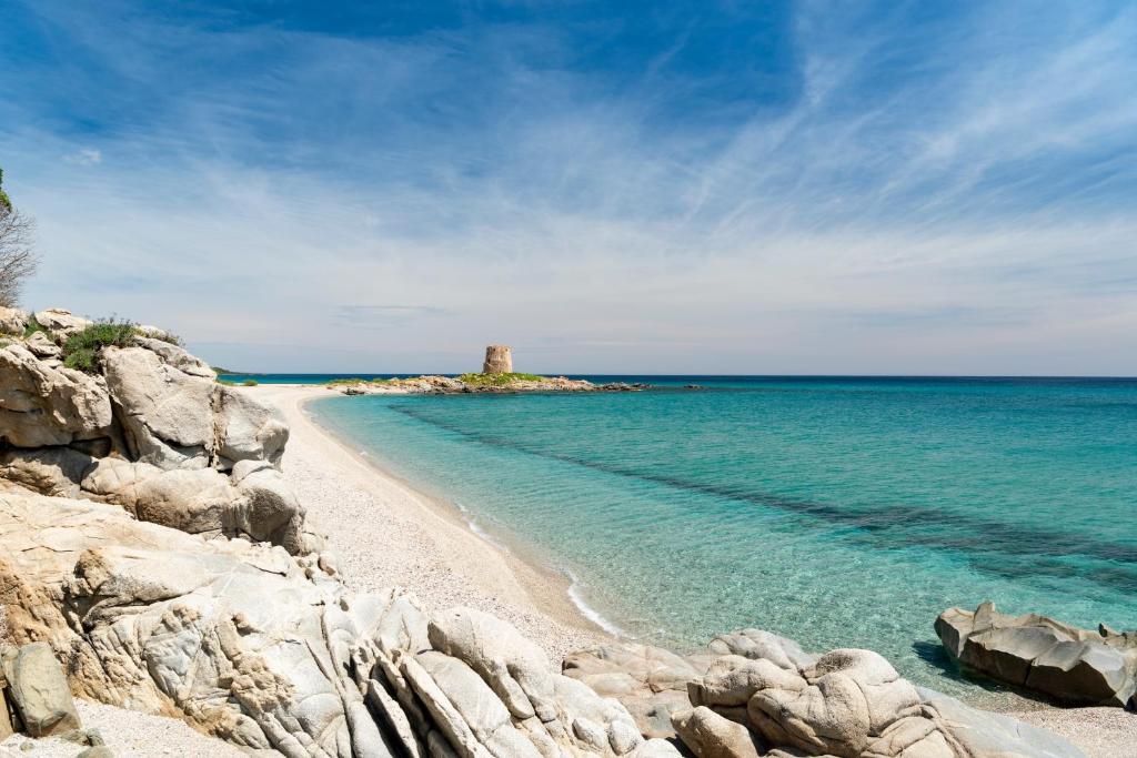 a beach with a lighthouse in the middle of the ocean at Casa Vacanze il mirto in Bari Sardo