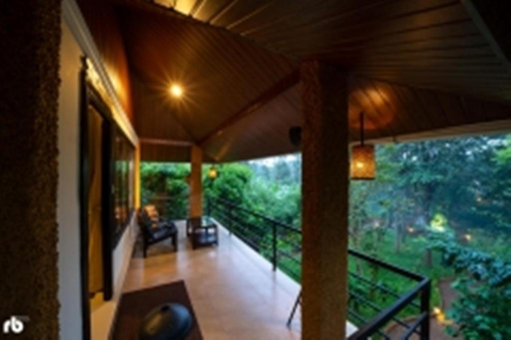 a porch of a house with a view of the forest at Kuruva Isles Jungle Resort in Wayanad