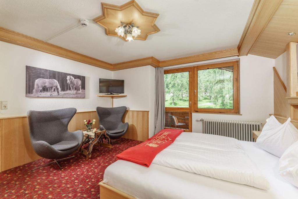 ein Hotelzimmer mit einem Bett und zwei Stühlen in der Unterkunft Naturhotel Lärchenhof in Ramsau am Dachstein