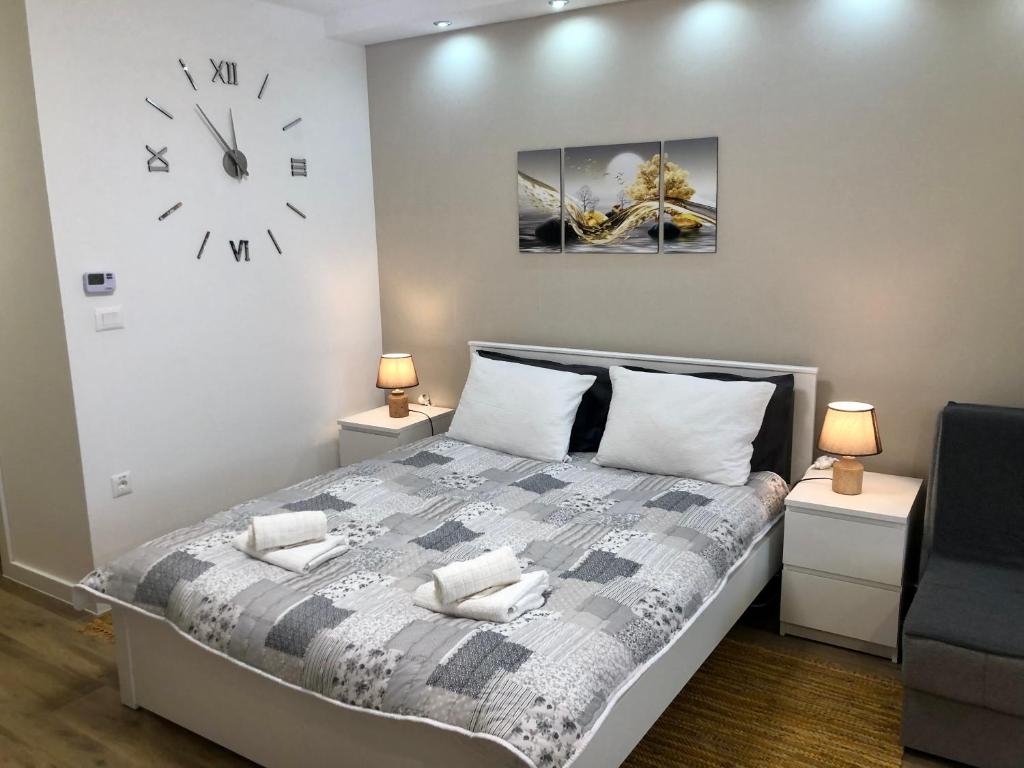 a bedroom with a bed and a clock on the wall at Apartments Biro in Subotica