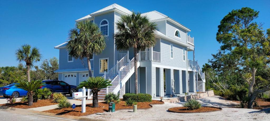 a blue house with palm trees in front of it at Luxury Vacation Home near Johnson Beach in Perdido Key