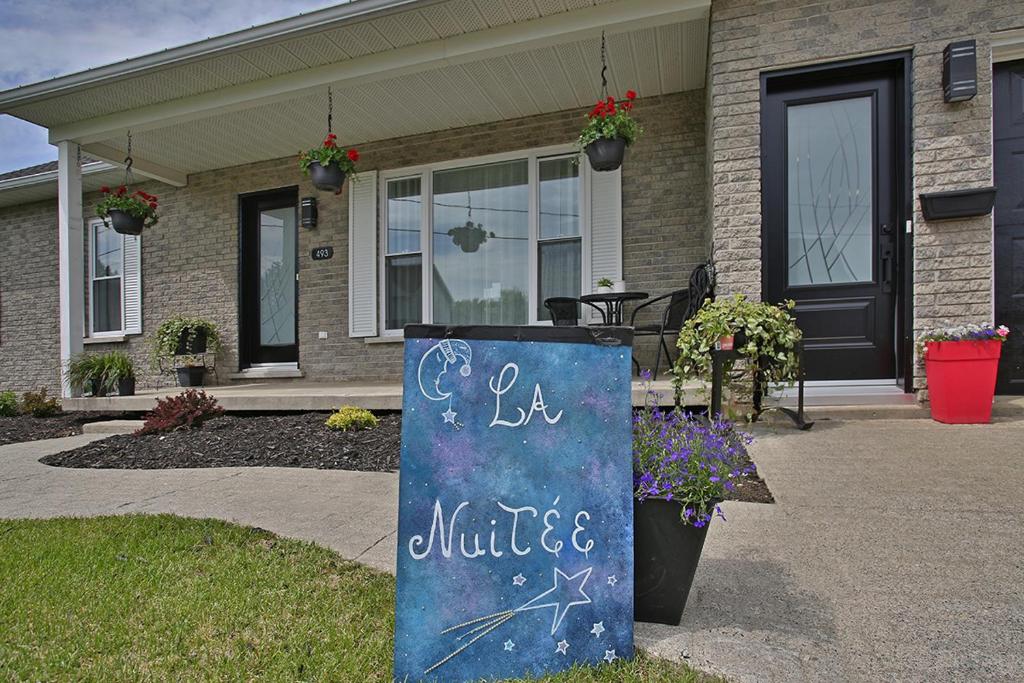 una casa con un cartel de pizarra delante de ella en Gîte La Nuitée en Coaticook