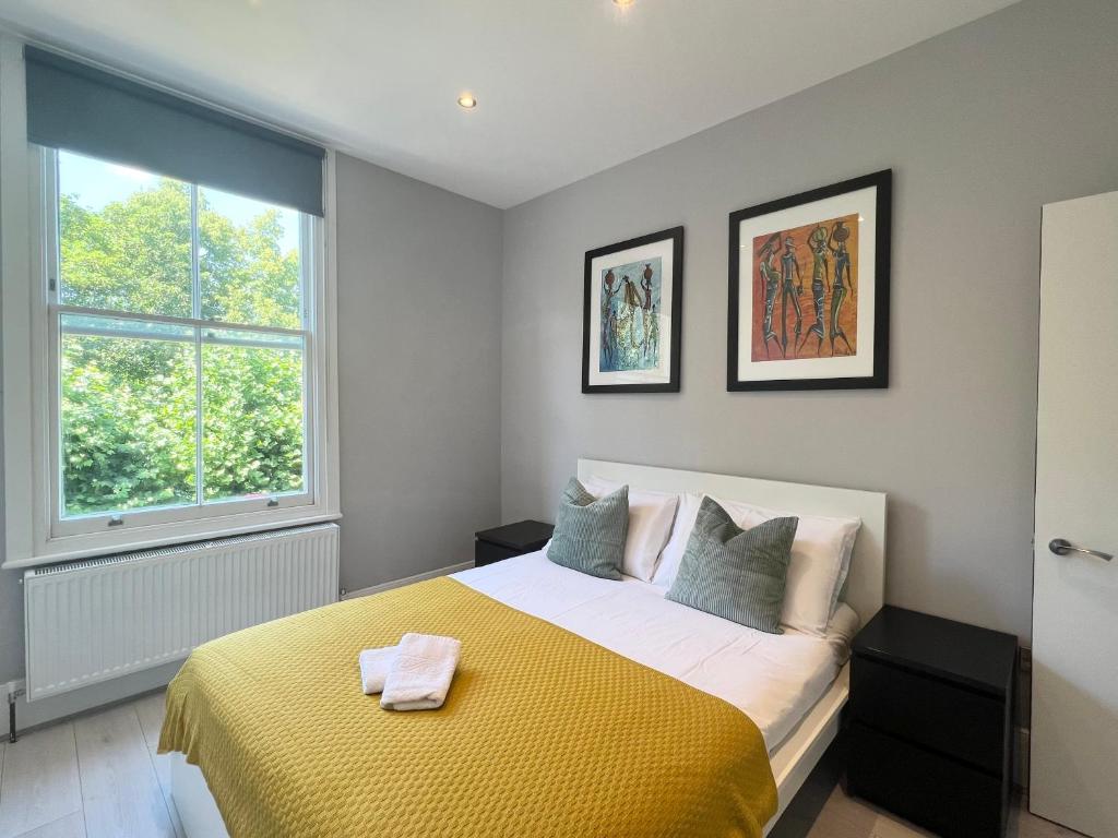 a bedroom with a bed with a yellow blanket at 2 Bedroom Apartment in South Hampstead in London