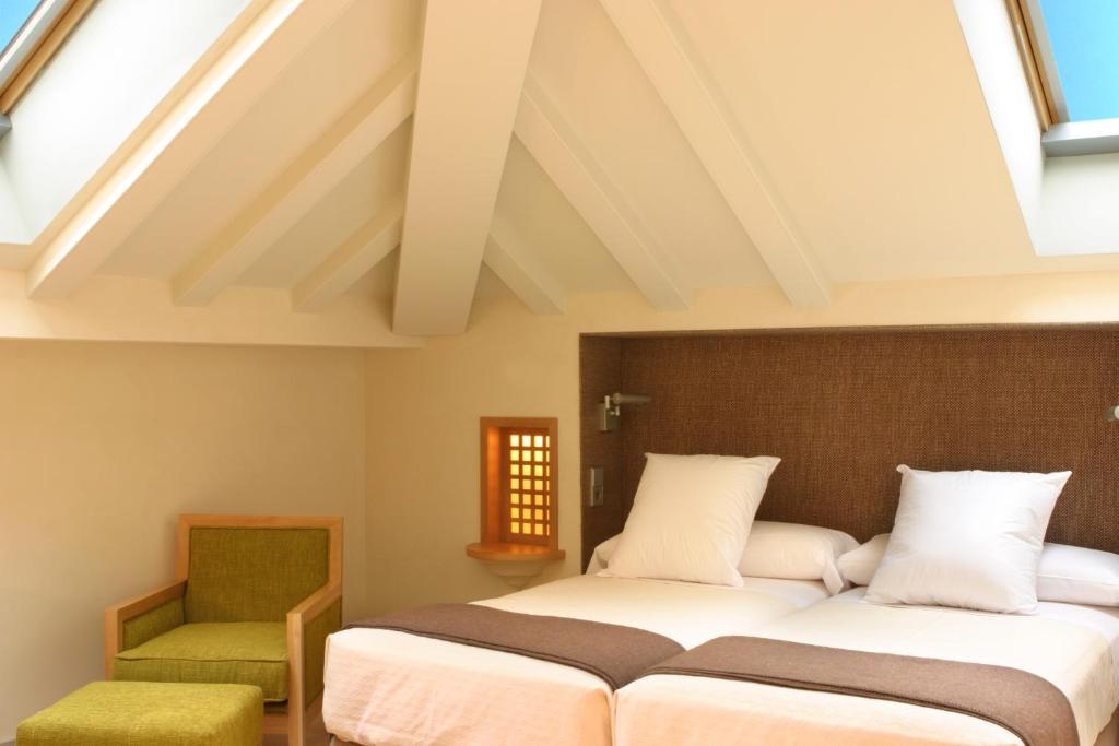 a bedroom with two beds and a green chair at Villa Oniria in Granada