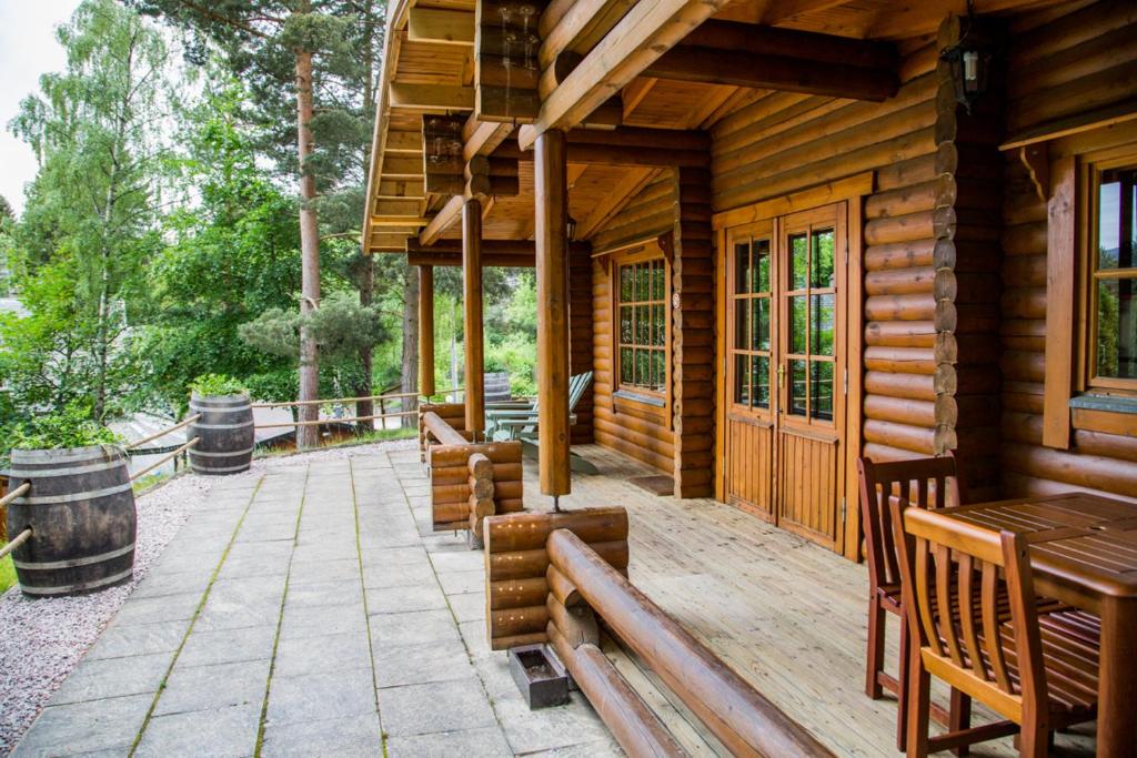 un porche de una cabaña de madera con bancos y mesas en Bynack, en Aviemore