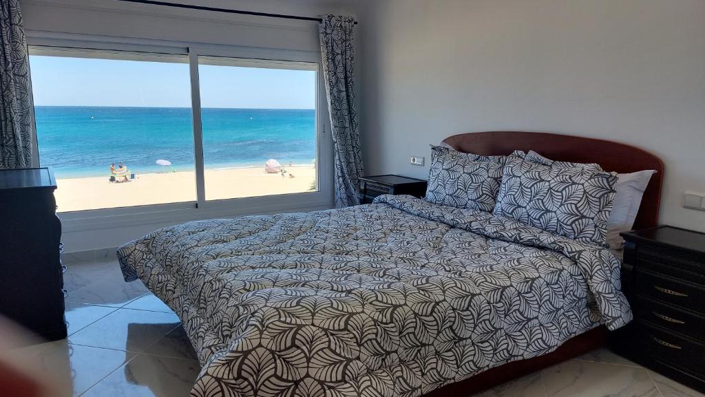 Schlafzimmer mit einem Bett und Strandblick in der Unterkunft Al amine plage in Fnideq