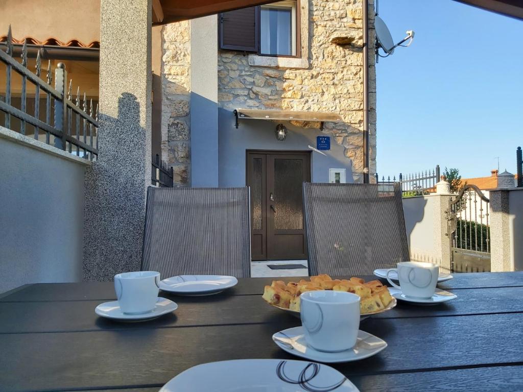 ein Tisch mit Tassen und Teller mit Essen drauf in der Unterkunft Kuća za odmor Lazarić in Marčana