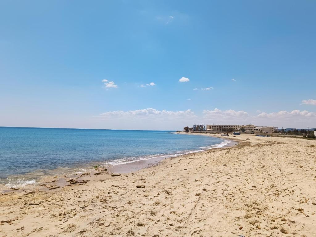 a sandy beach with the ocean and buildings in the background at Superbe étage de villa vue sur mer in Nabeul