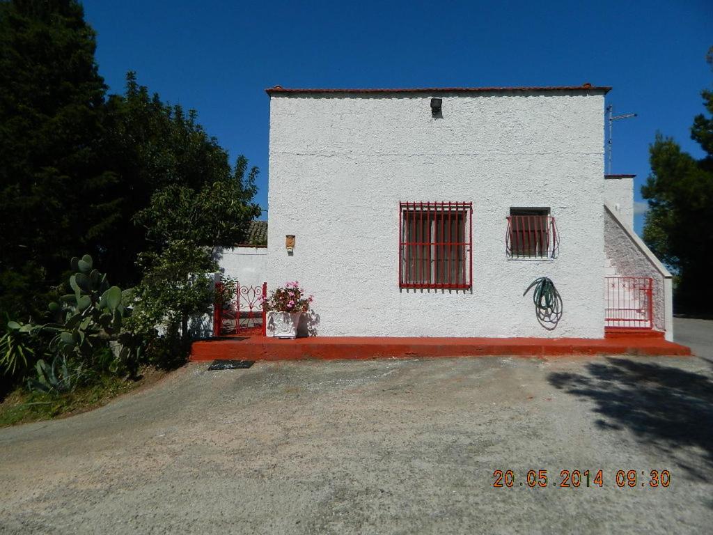 um edifício branco com janelas com barras vermelhas numa rua em Rustic cottage in Montalbano jonico em Montalbano Ionico