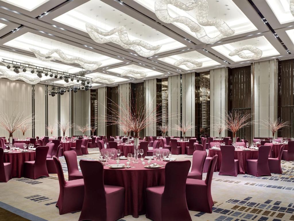 廈門市にあるLangham Place Xiamenのシャンデリアのある部屋にテーブルと椅子のある宴会場