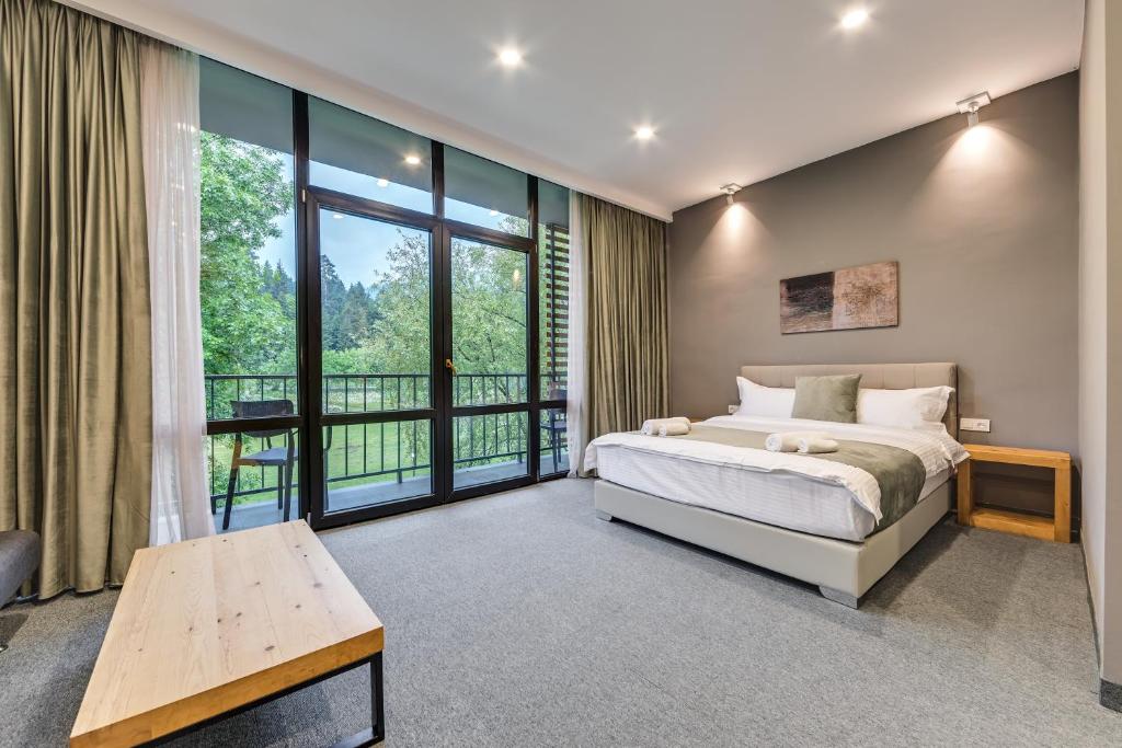 a bedroom with a bed and a large window at Mountain Resort Gantiadi in Borjomi
