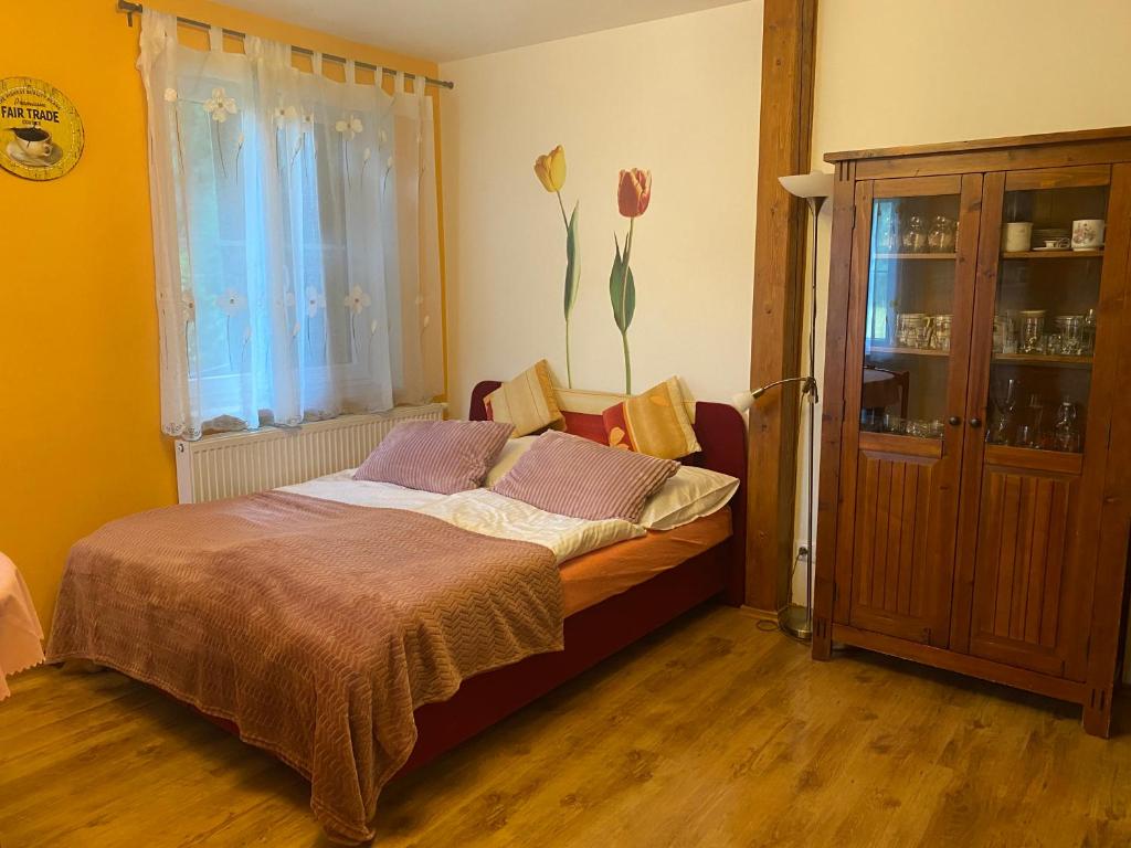 ein Schlafzimmer mit einem Bett und einem Fenster mit Blumen in der Unterkunft Alba Apartmany Železná Ruda in Železná Ruda
