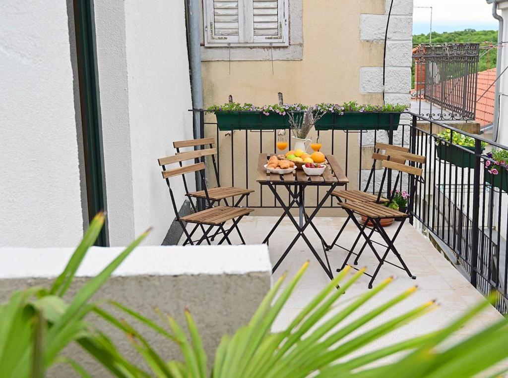 a balcony with chairs and a table with fruit on it at Apartment D & Studio L in Dobrinj