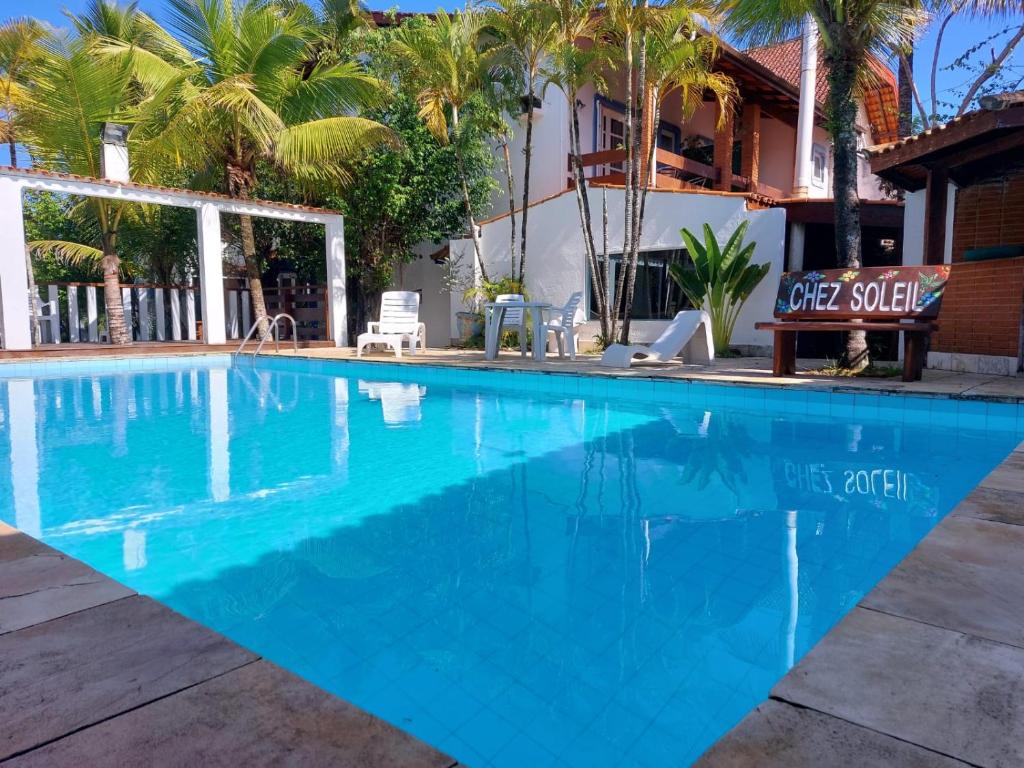 una piscina en un complejo con palmeras en Pousada Chez Soleil CibrateI Itanhaém, en Itanhaém