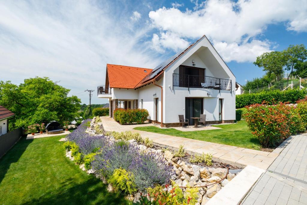 a white house with an orange roof and a garden at Pilger Apartments in Tihany