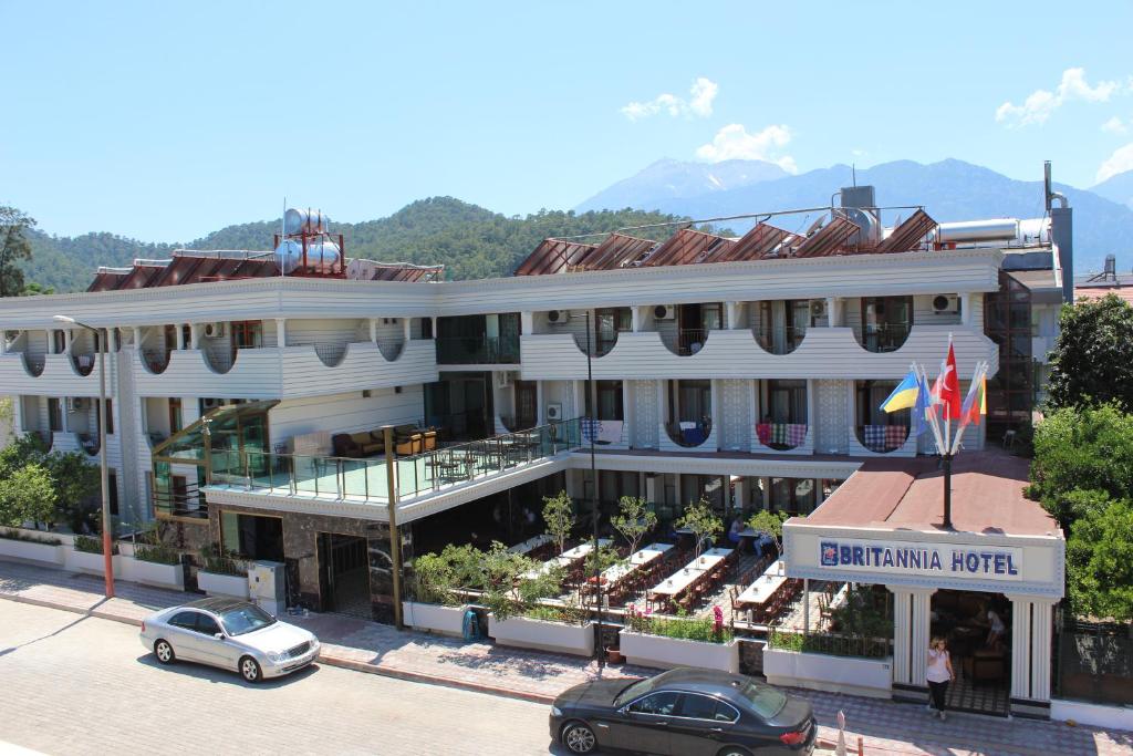 a large white building with cars parked in front of it at Britannia Hotel Village in Kemer