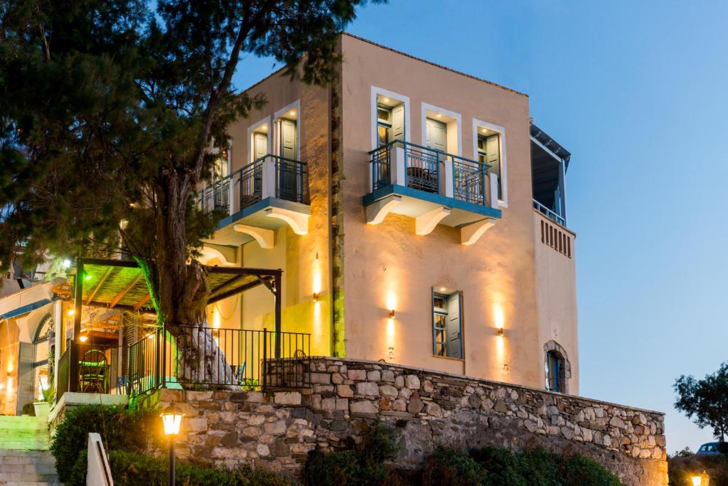 a large white building with a stone wall at Captain's House Hotel Suites & Apartments in Panormos Rethymno