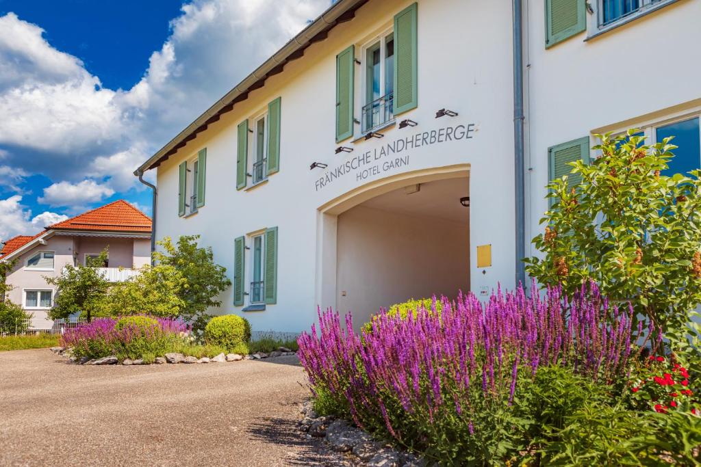 Fränkische Landherberge, Hotel Garni في Seßlach: مبنى امامه كراج وزهور