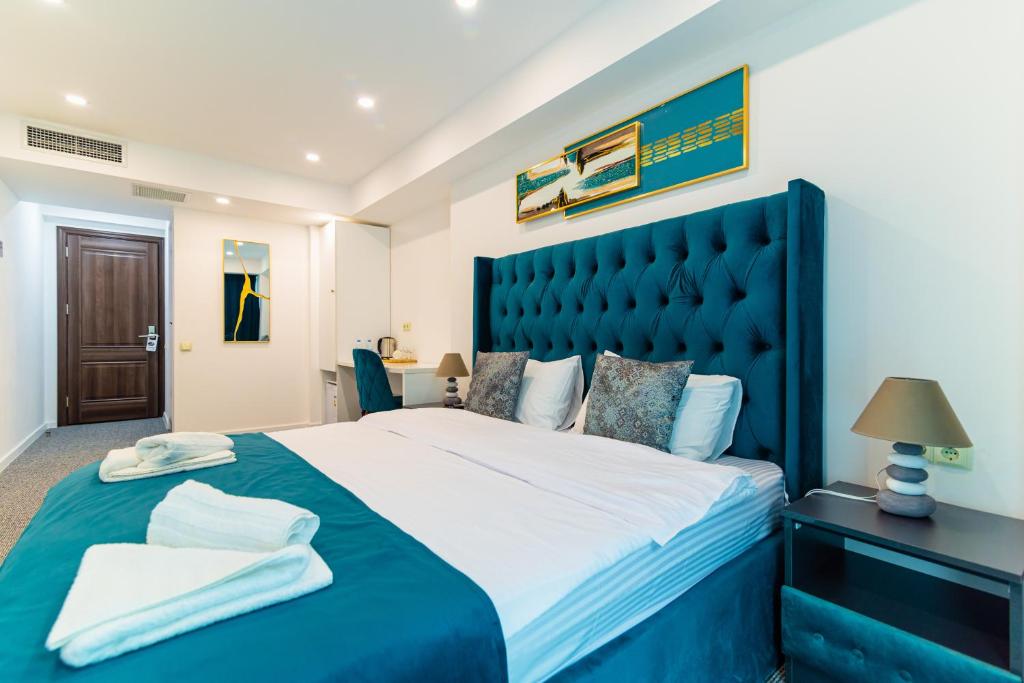 a bedroom with a large bed with a blue headboard at Royal Plaza Hotel in Tbilisi City