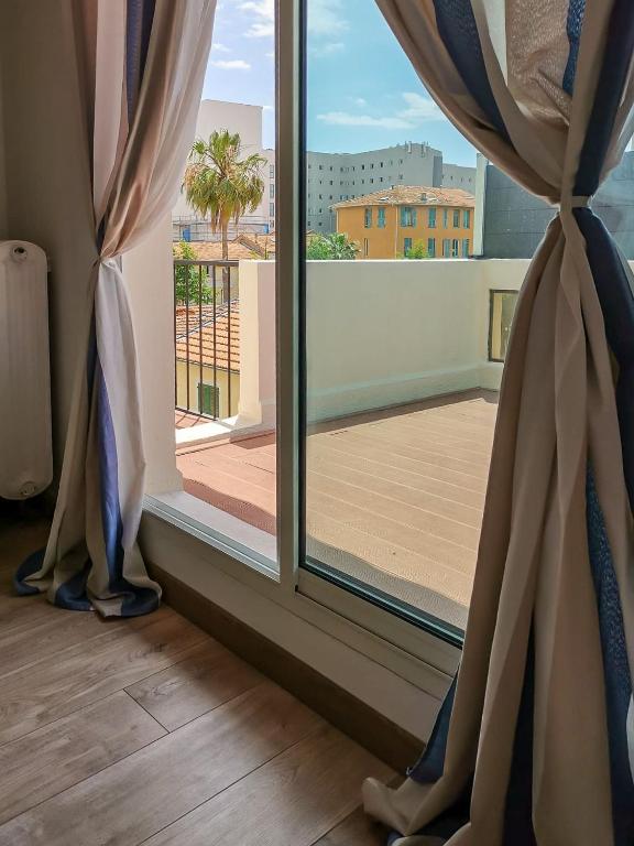 une fenêtre ouverte avec vue sur un balcon dans l'établissement Magnifique appartement vacances proche de la mer, à Nice