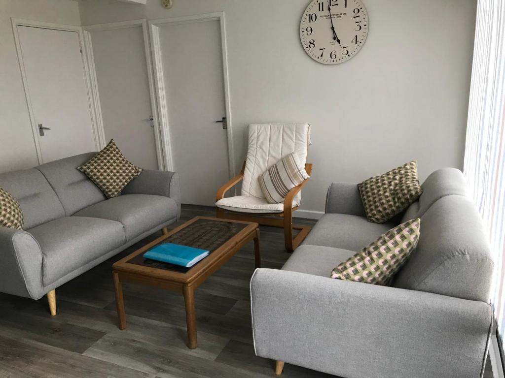 una sala de estar con 2 sofás y un reloj en la pared en 310 Norton Park en Dartmouth
