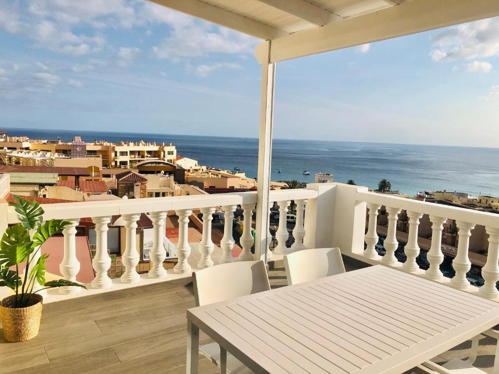 een balkon met een tafel en stoelen en de oceaan bij House Sofi , Morro Jable Ftvra. Canary Islands. in Morro del Jable