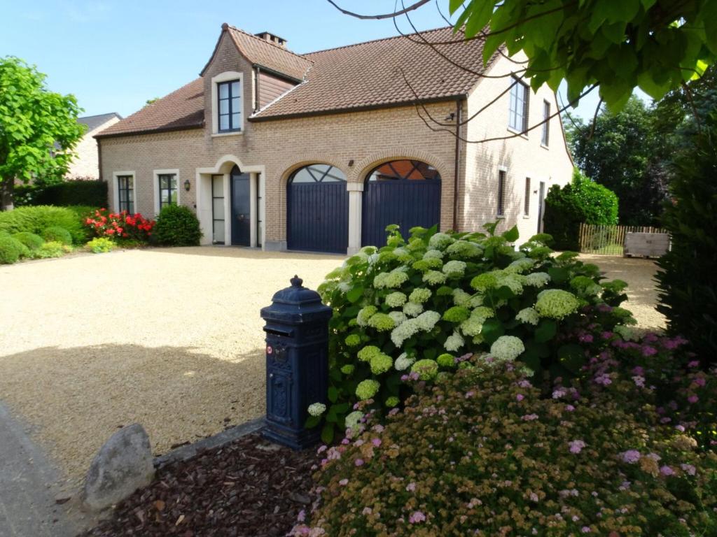 a house with a blue fire hydrant in a yard at Pleasant Holiday Home in Heers with Outdoor Sauna in Heers