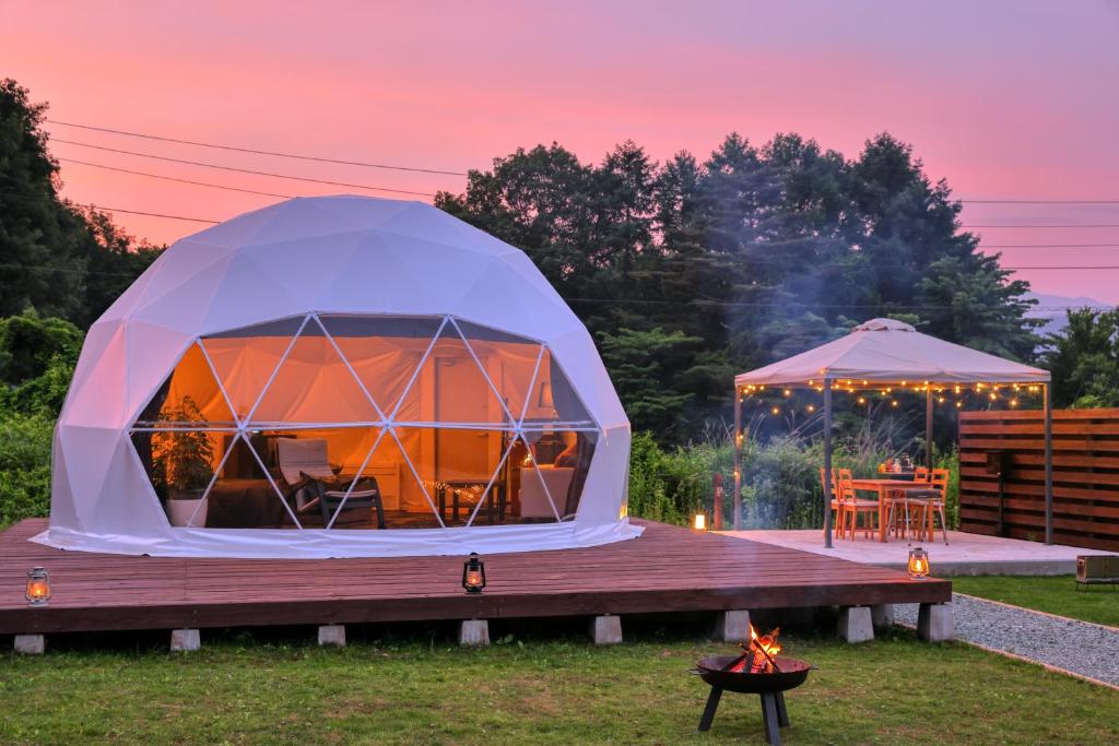 Glamping Resort Varie في فوجيكاواجوتشيكو: خيمة كوخ القباني مع طاولة وشواية