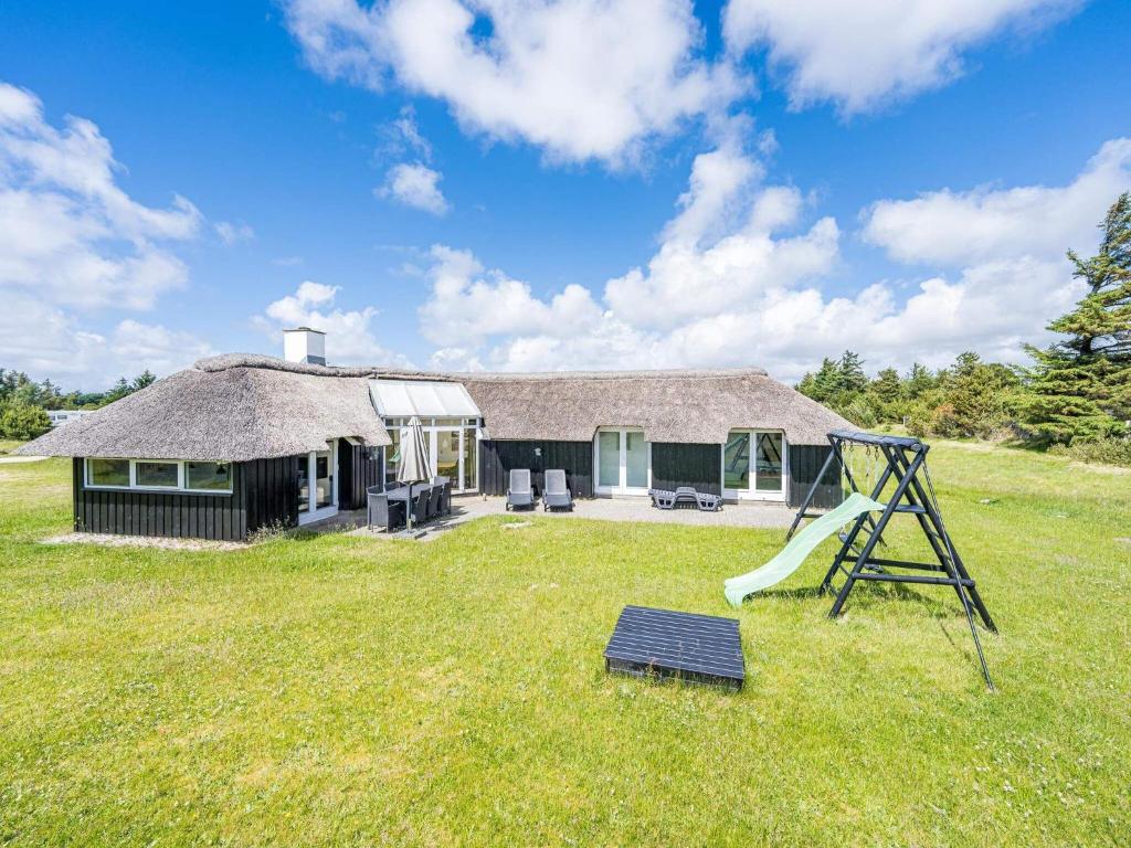 a house with a slide and a playground at 6 person holiday home in Vejers Strand in Vejers Strand