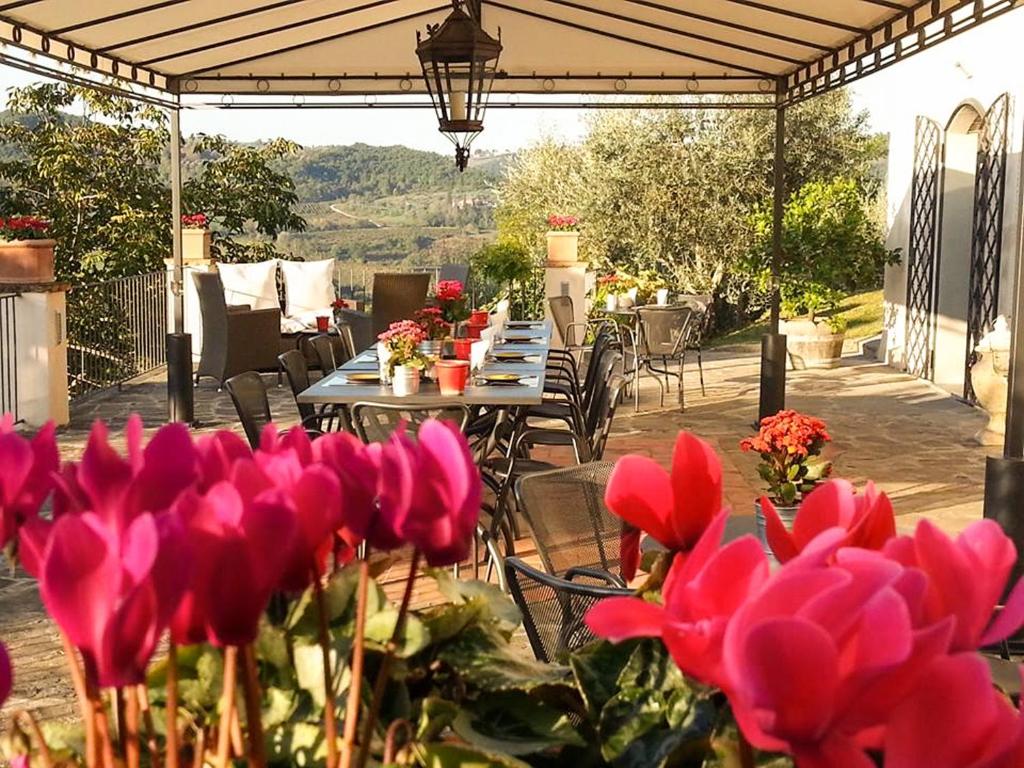 um grupo de mesas com flores cor-de-rosa num pátio em B&B Le Dimore Mezza Costa em San Casciano in Val di Pesa