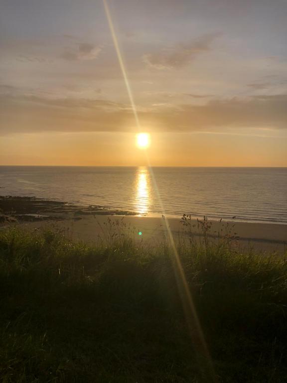 zachód słońca nad oceanem z zachodem słońca w obiekcie Gwel y Môr - Lleyn Peninsula Static w mieście Llangwnadl