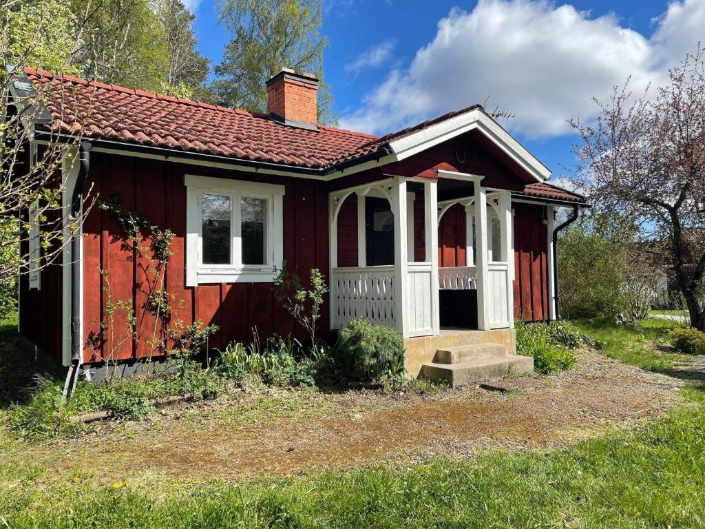 une petite maison rouge avec un toit rouge dans l'établissement Holiday home ÖSTERBYBRUK, à Gimo