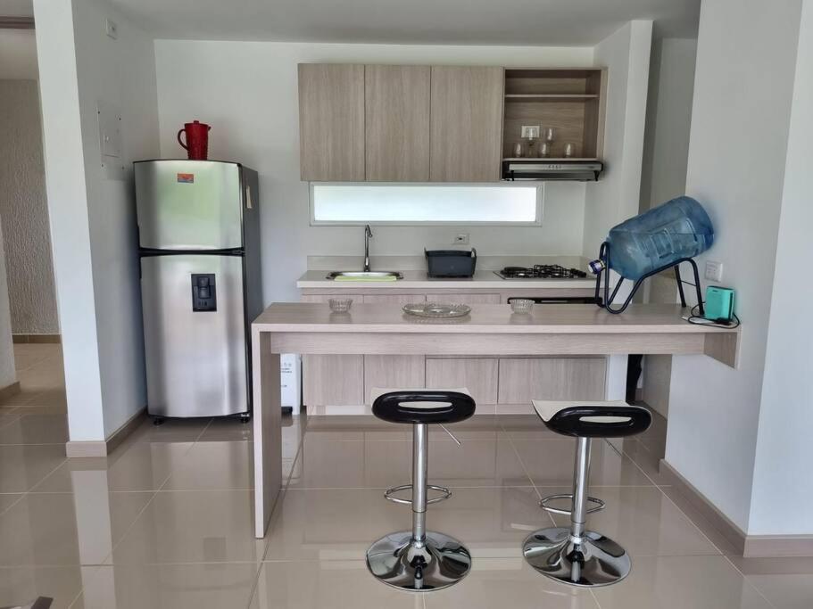 a kitchen with a counter with two stools and a refrigerator at Hermoso apartamento en SANTA FE DE ANTIOQUIA in Medellín