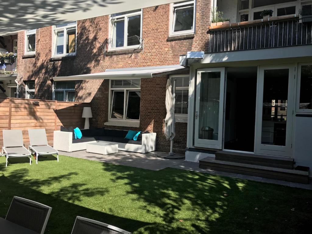 une terrasse avec des chaises et une pelouse en face d'un bâtiment dans l'établissement Amsterdam, 120 sqm Design flat with garden, close to all!, à Amsterdam