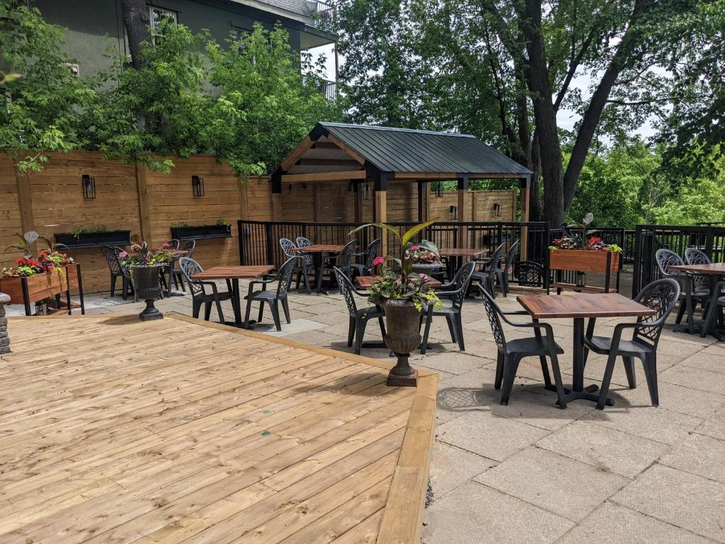 a wooden deck with tables and chairs and a gazebo at Inn at the Falls in Bracebridge