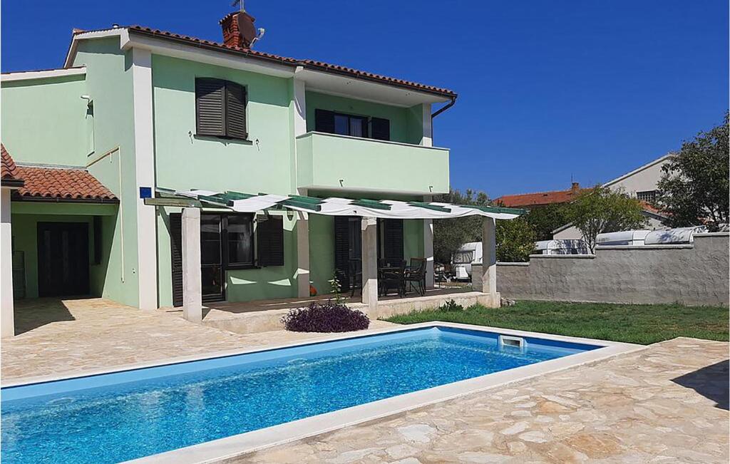 une maison avec une piscine devant une maison dans l'établissement Nice Home In Liznjan With Wifi, à Ližnjan