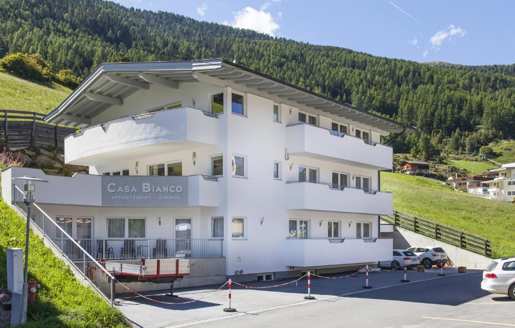 een groot wit gebouw op een heuvel met een parkeerplaats bij Casa Bianco in Sölden