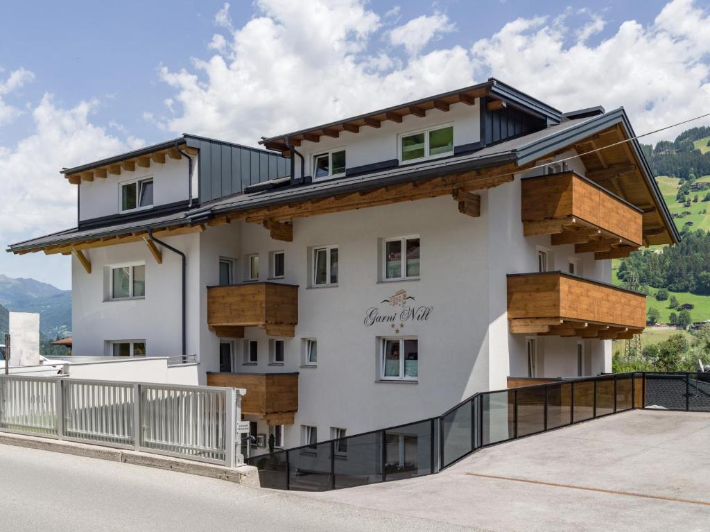 ein großes weißes Gebäude mit Holzbalkonen darauf in der Unterkunft Garni Nill in Schwendau