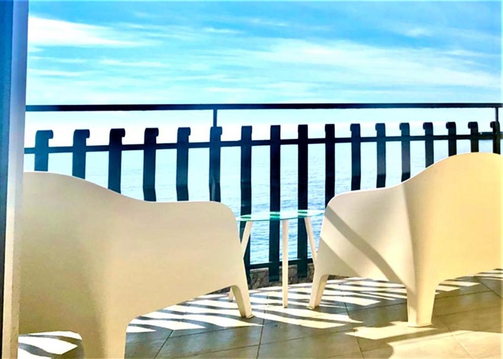 - un balcon avec deux chaises et une table donnant sur l'océan dans l'établissement VacanzeNaxos - Casa Frontemare, à Giardini Naxos