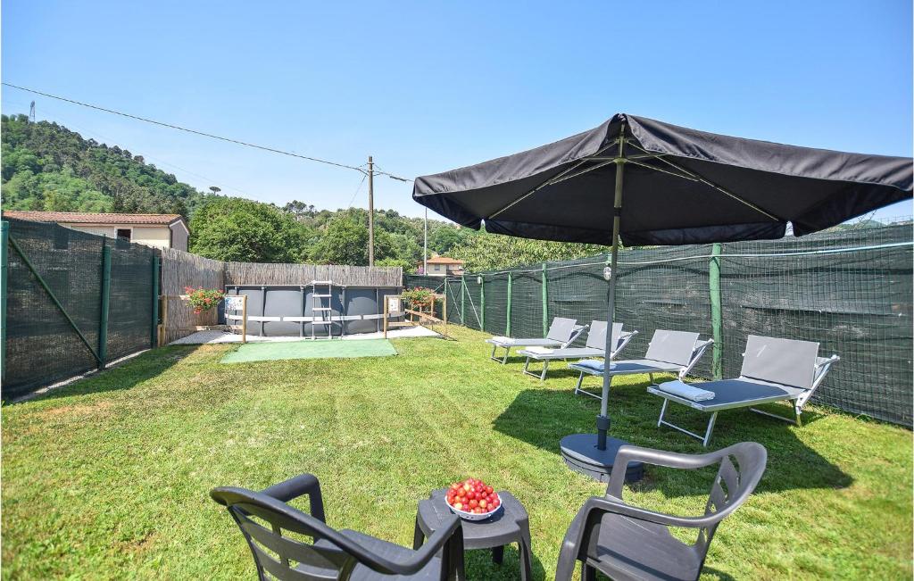 a patio with chairs and an umbrella on the grass at Nice Home In Camaiore With Kitchen in Camaiore