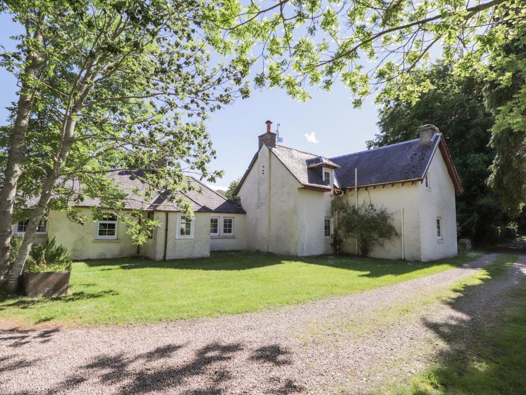 an exterior view of a white house with a driveway at Garden Cottage in Elgin