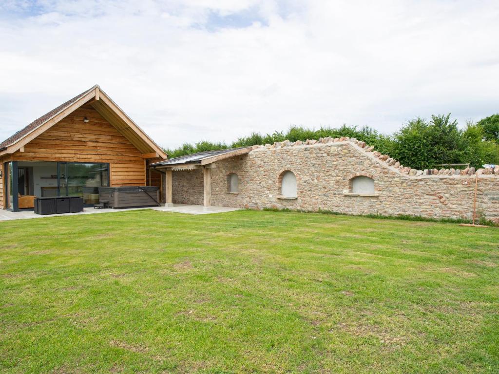 a stone house with a stone wall and a yard at Owl Lodge in Wedmore